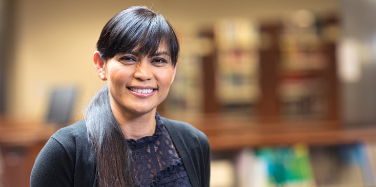  woman with bangs and long ponytail standing in a library