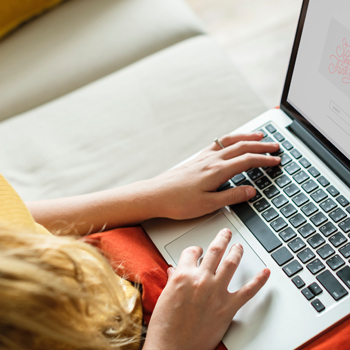 closeup of a woman sitting on a couch with a laptop in her lap