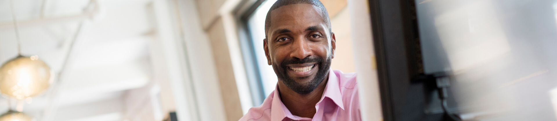 Man in a button down shirt smiles at the camera for the Graduate Certificate in Banking Program Page