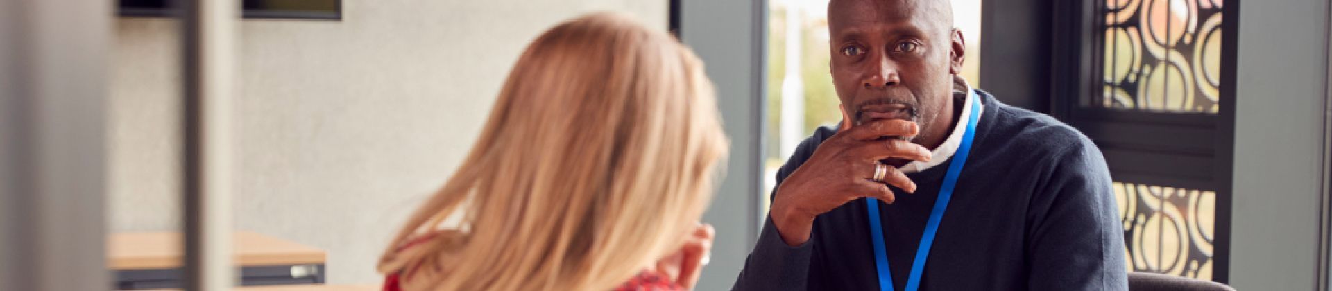 Black professional man looking concerningly at student whose back is turned towards camera but appears to be crying