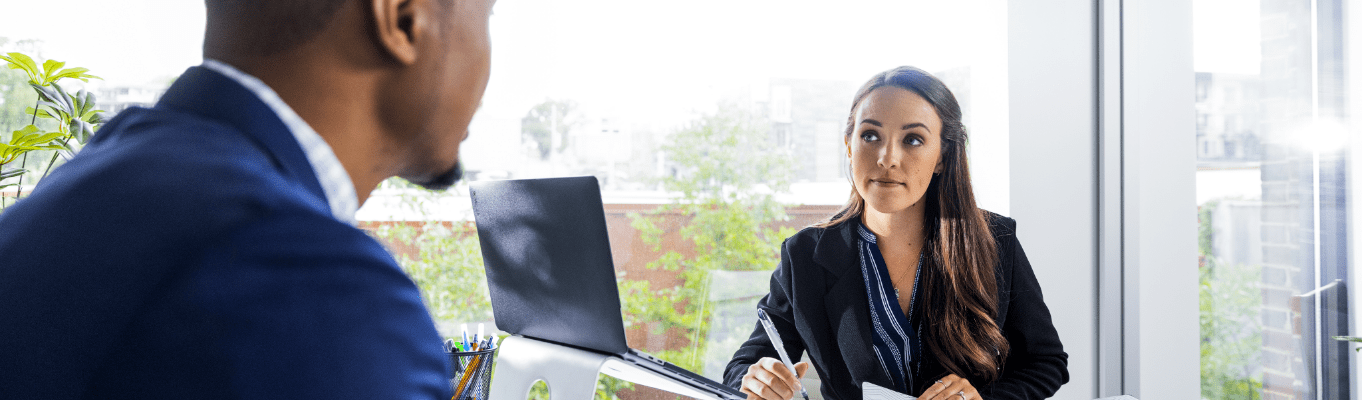 two business professionals sitting at a desk discussing a business administration degree