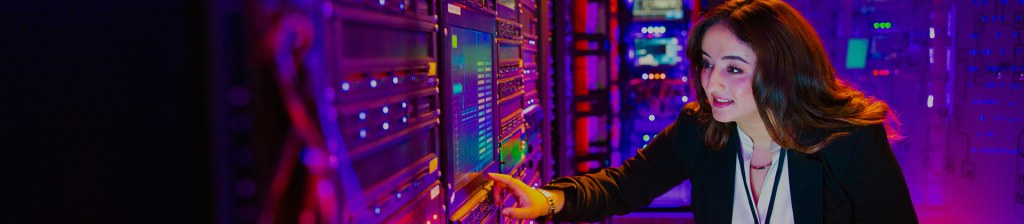 woman in server room pointing at screen